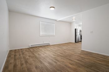 A room with wooden flooring and a window with blinds.